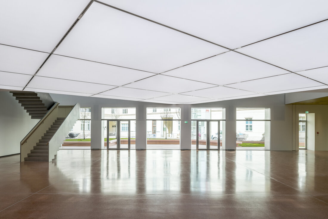 Horten-Collection Museum Foyer im EG, Blick auf die Glastüren der Außenfassade, dem Treppenaufgang und der Lichtdecke mit tunable white LED-Modulen